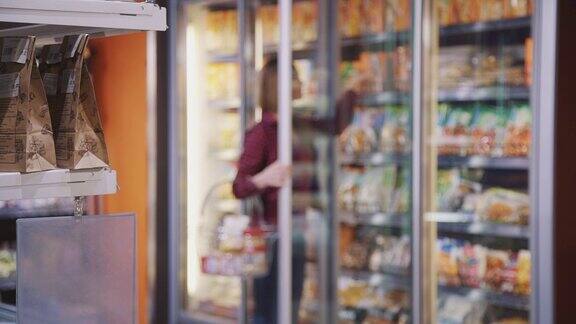 迷糊的女人打开冰箱的玻璃门自信地从架子上拿食物