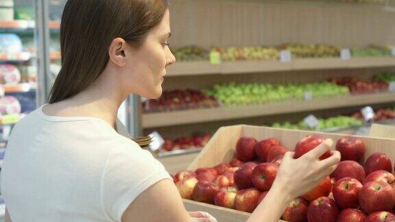 年轻女子在杂货店购买健康食品素食女孩选择新鲜的红苹果