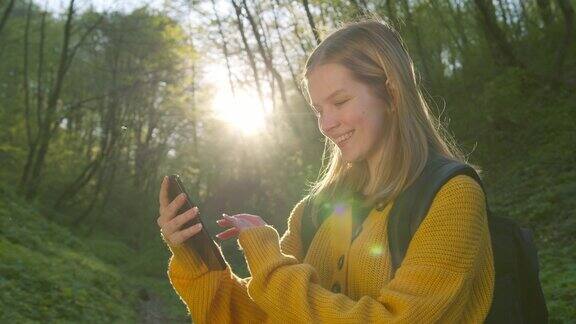 那个女孩正在看智能手机上的地图在森林里徒步旅行4k