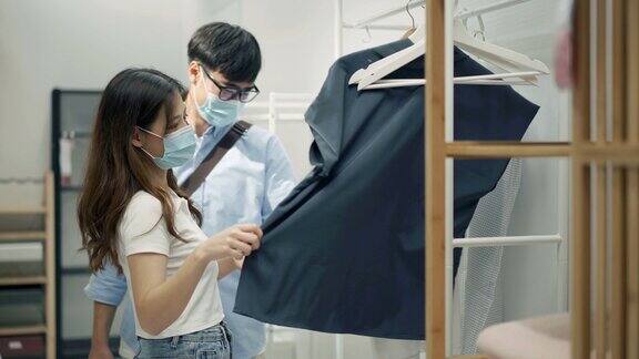 4K年轻夫妇戴着防护口罩在购物中心挑选衬衫