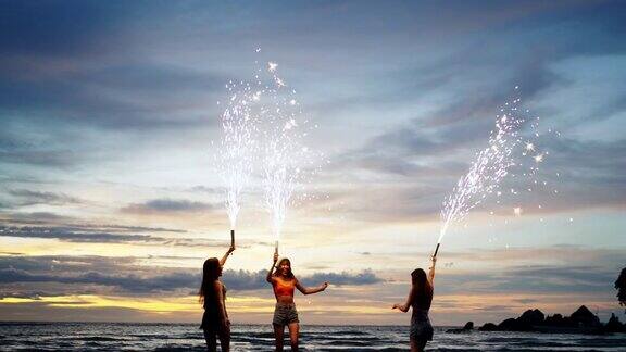 4K一群亚洲女人在夏夜的热带海岛海滩上一起玩烟火