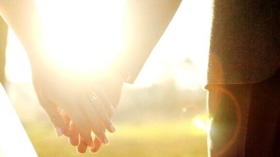 婚礼夫妇牵着手在日落背景在慢动作近距离拍摄