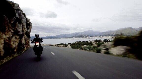 骑摩托车旅行的年轻女子多岩石的海岸线