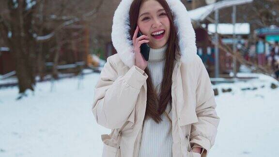 亚洲女性旅行者在户外雪地旅行概念中通过智能手机或视频通话进行交谈