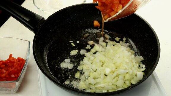 厨师在煎锅中加入红椒片、洋葱片、番茄片