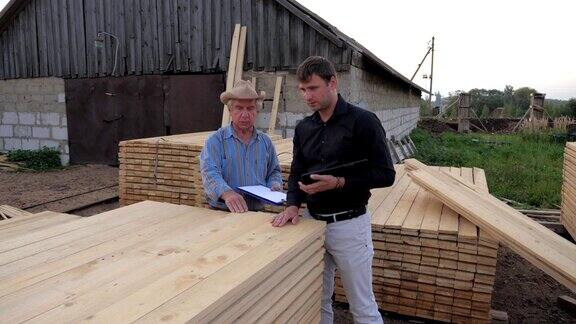 买家和卖家在锯木厂拿起一块木板检查它