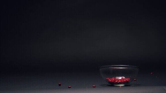 红色糖果在玻璃碗中缓慢下落复制空间在黑色黑板纹理背景上