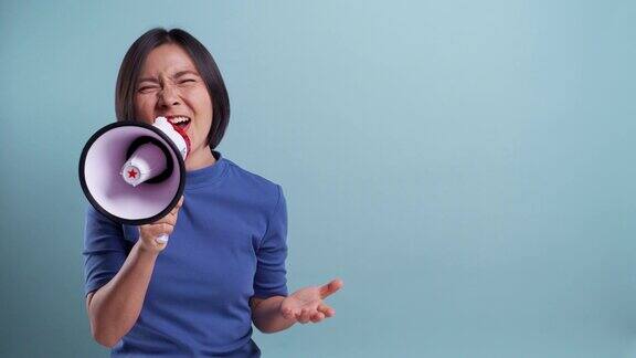 快乐的亚洲女人用扩音器做呼喊手势孤立的蓝色背景4k的视频