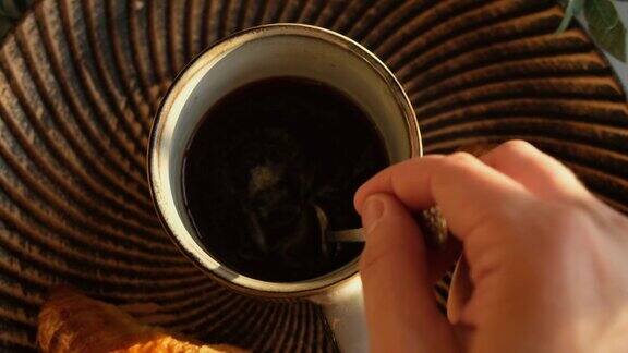 女人用勺子在咖啡杯里搅拌糖