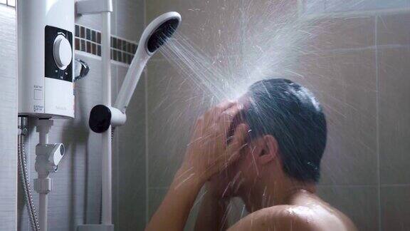 年轻的亚洲男人在浴室里用淋浴洗澡充满新鲜感