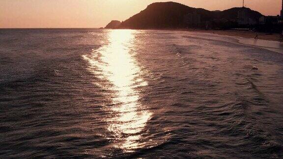 夕阳洒在大海海浪沙滩上航拍
