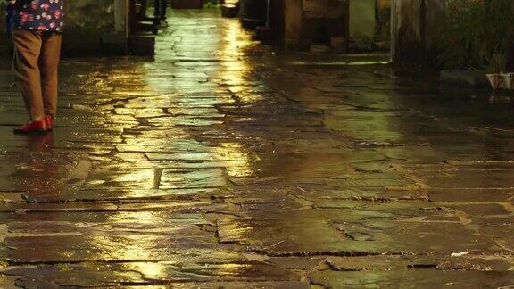 夜晚的古街光影：雨后石板路行人剪影 