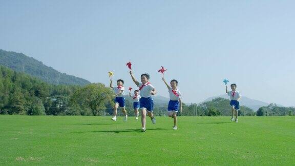 小孩在草地奔跑玩纸风车