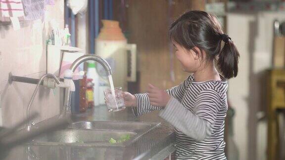 一个小女孩用玻璃杯装水的镜头