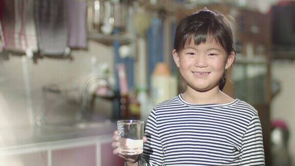 一个小女孩用玻璃杯装水的镜头