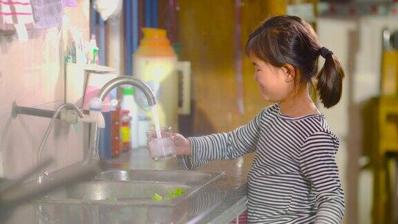 小孩在厨房用玻璃杯装水