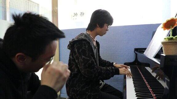 大学老师教男学生学习弹钢琴