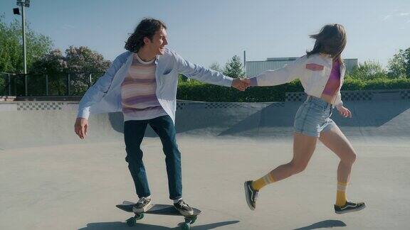 女孩拉着男孩的手练习滑板跑